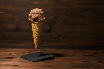 funny creative concept of flying wafer cone with chocolate ice cream on wooden background, concept, copy space