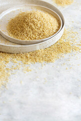 Raw Dry bulgur wheat grain on a plate close up, copy space. Vegetarian and Middle Eastern cuisine
