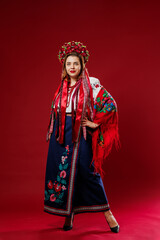 Portrait of ukrainian woman in traditional ethnic clothing and floral red wreath on viva magenta studio background. Ukrainian national embroidered dress call vyshyvanka. Pray for Ukraine