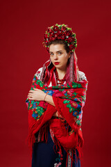 Portrait of ukrainian woman in traditional ethnic clothing and floral red wreath on viva magenta studio background. Ukrainian national embroidered dress call vyshyvanka. Pray for Ukraine