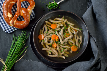 Kräftige  Rinderbrühe mit Leberspätzle auf einer Schieferplatte mit einer bayerischen Breze...