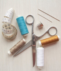 Fototapeta na wymiar Sewing accessories, threads, needles, scissors, thimble on a white table. Sewing and hobby concept.