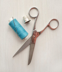 Sewing accessories, threads, needles, scissors, thimble on a white table. Sewing and hobby concept.