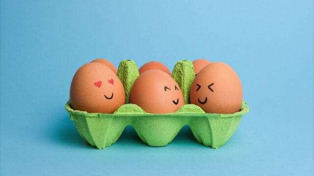 Cute easter eggs with funny faces in green box isolated on blue background. Happy easter concept. Stop motion easter animation.