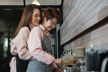 young asian woman LGBTQ lesbian couple working and teasing each other in business owner coffee shop. concept for LGBTQ lifestyle, cohabitation, relationship etc