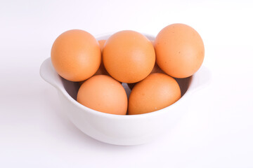 Fresh chicken eggs in a white bowl on a white background