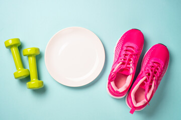 Dumbbells, white plate and sport shoes on blue. Healthy lifestile, fitness, diet and weight loss concept.