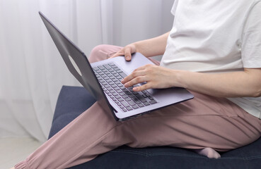Naklejka premium Pregnant woman in white clothes sitting and using laptop in sofa. Baby expectation. Homely atmosphere.