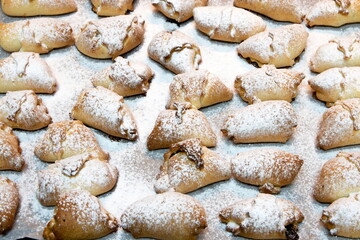 Fototapeta na wymiar Sweet homemade croissants sprinkled with vanilla sugar. Small buns from the oven on a baking sheet. Delicious buns sprinkled with vanilla sugar