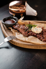 Sliced meat on a wooden board with sauces side view