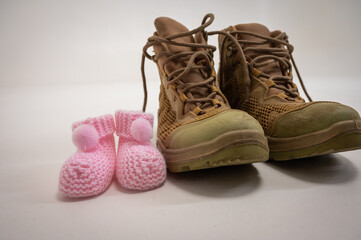 Men's boots and children's shoes. Expecting a child, a girl. On a light background