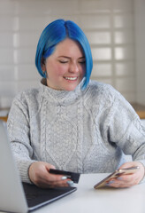 Fototapeta premium Happy young woman paying online with credit card. Portrait of female person using modern smart phone and plastic bank card for payment