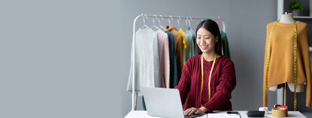 Asian beautiful cloth owner using laptop computer while planning her new concept for her new...