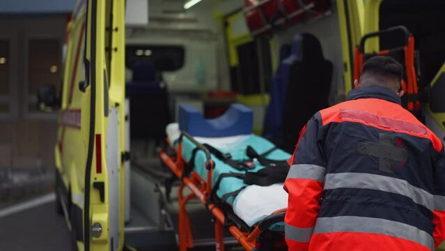 Rescuer getting empty stretcher inside ambulance vehicle.