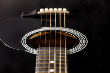 Guitar black, polished smooth soundboard, stretched strings, close-up selective focus