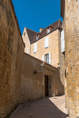 the steep road to the beynac castle with old limestone walls and houses