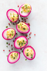 A vertical view of several creamy and delicious bright pink devilled eggs.