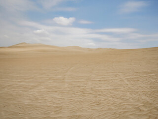 A wide view of the desert with truck tracks and clear blue skies during the day
