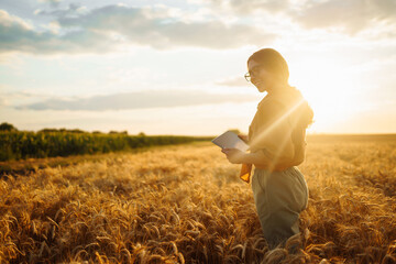 Young Female farmer with tablet in the field. Agriculture, gardening, business or ecology concept. Growth dynamics.