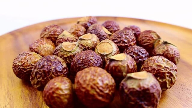 Brown dry soap nuts (Soapberries, Sapindus Mukorossi, Reetha) for organic laundry and gentle natural skin care circle rotation close up