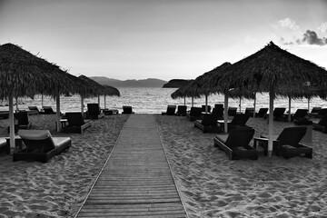 View of a wooden path leading to the stunning beach of Mylopotas in Ios Greece at sunset in black...