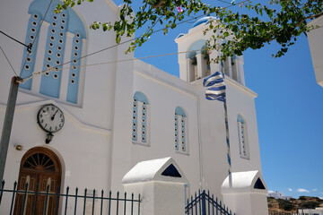 View of a beautiful whitewashed orthodox cathedral in Ios Greece and the Greek national flag