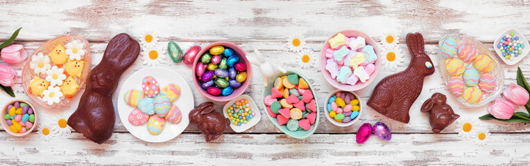 Easter candy table scene. Above view over a white wood banner background. Chocolate bunnies, candy...
