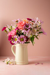 Beautiful fresh flowers. Pink bouquet of flowers in vase, on pink background.