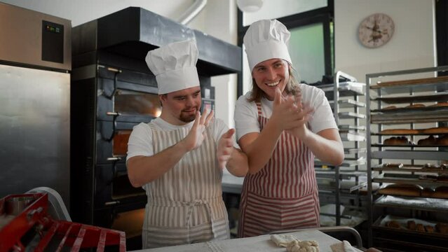 Video of man with down syndrom and his colleague in bakery. Concept of integration people with disability into society.