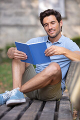 man holds a notebook sitting on a bench