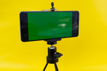 Black mini tripod with steel case, ballhead and smartphone with greenscreen
