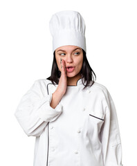 Young caucasian cook woman isolated is saying a secret hot braking news and looking aside
