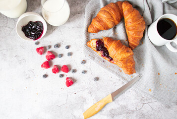 Breakfast with coffee and croissants, jam and berries. On a concrete background