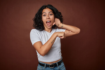 Young colombian curly hair woman isolated on brown background trying to listening a gossip.
