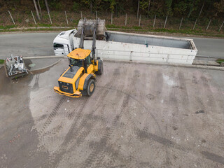 Skid steer loader loading a truck with waste material transferred for further sorting, treatment,...