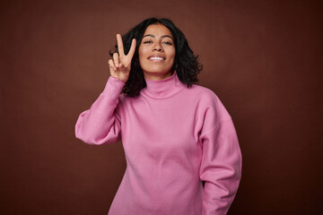 Young colombian curly hair woman isolated on brown background showing number two with fingers.