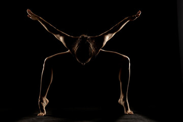 Obraz premium Art silhouette of a young woman doing yoga exercise. Yoga pose on black background.