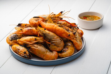 Grilled Giant Prawn in white plate serve with seafood sauce.