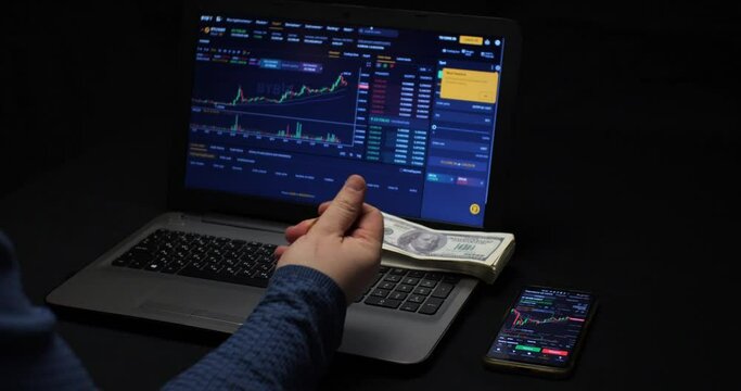 A man throws a bitcoin coin for good luck on the background of a laptop with a cryptocurrency chart. A man earns on cryptocurrency. The concept of a cryptocurrency trader on the stock exchange.
