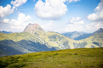 Obraz na płótnie Canvas rocky mountain with lush greenery below and blue sky with clouds