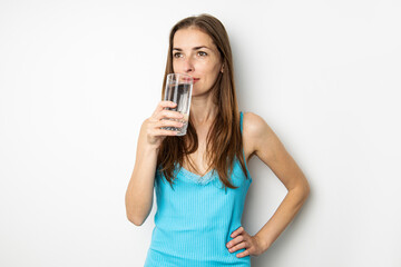 Young woman drinking water from a glass on a white background