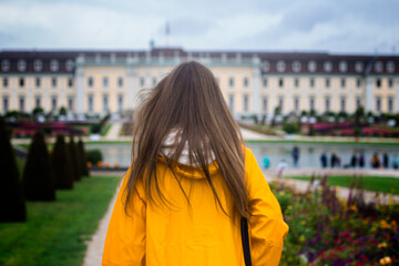Fototapeta na wymiar Young woman with her back in a yellow raincoat in the park