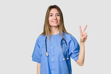 Young female nurse in uniform with stethoscope, symbol of care and dedication to patients showing a mobile phone call gesture with fingers.