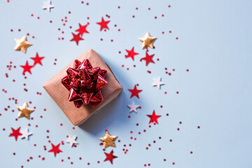 Greeting card for the Defender of the Fatherland Day. White, gold, red stars, a gift box and the number 23 on a light blue background. The holiday is February 23.