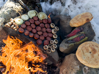 Camping meal preparation over wood fire and count stone