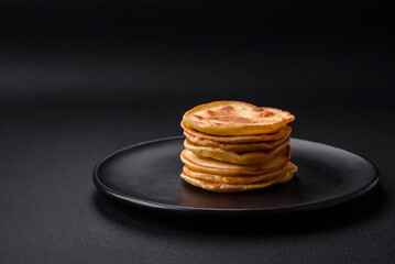 Delicious fresh pancakes with berry jam on a black ceramic plate