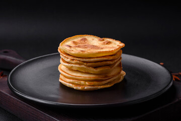Delicious fresh pancakes with berry jam on a black ceramic plate