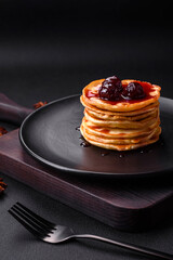 Delicious fresh pancakes with berry jam on a black ceramic plate