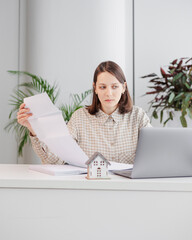 female design engineer working in office holds mock-up of house in hands. career in large company...