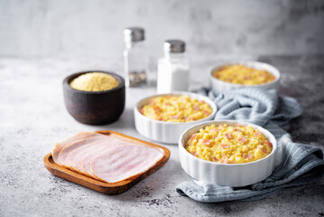 Cheesy millet with ham slices in a baking bowl